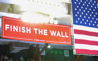 Trump election event with banner saying "Finish the wall"