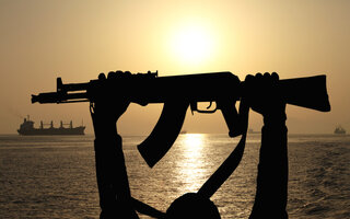 silhouette of machine gunin front of ship