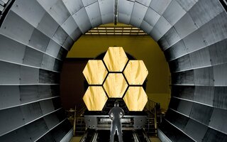 Man standing in front of large space telescope 
