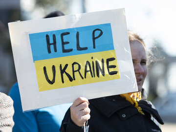 Woman holds up sign with words "Help Ukraine"