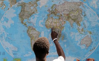 Man pointing to West Africa on a world map