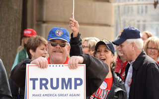 Protesters holding up a sign with "Trump" written on it.