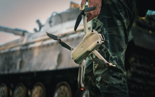 artillery spotter or military observer launches drone into sky force reconnaissance in enemy territory. drone control panel is in hand of military soldier