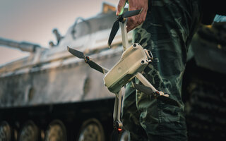 artillery spotter or military observer launches drone into sky force reconnaissance in enemy territory. drone control panel is in hand of military soldier
