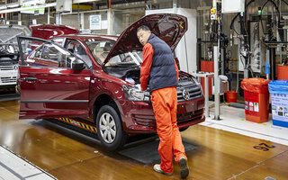 Arbeiter, der Autos auf der Montagelinie von Shanghai Volkswagen installiert / Worker who installs cars on the Shanghai Volkswagen factory assembly line