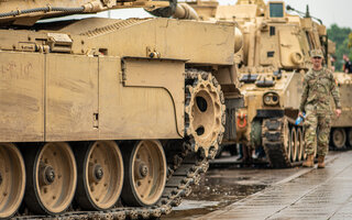 soldier standing under the rain near an armoured tank, NATO response force