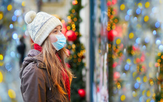 Mädchen trägt Gesichtsmaske auf einer Pariser Straße oder auf Weihnachtsmarkt / Girl wearing face mask on a Parisian street or at Christmas market looking at shop windows