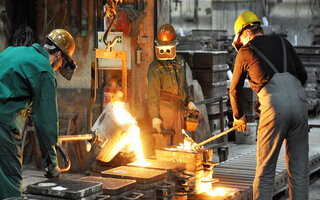 Gruppe von Arbeitern in einer Gießerei bei dem Schmelzofen / Group of workers in a foundry at the melting furnace