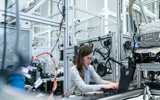 Frau am Computer in Werkhalle