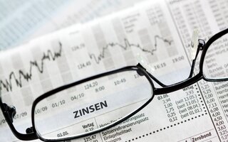 Glasses on a newspaper focused on the word "Zinsen"