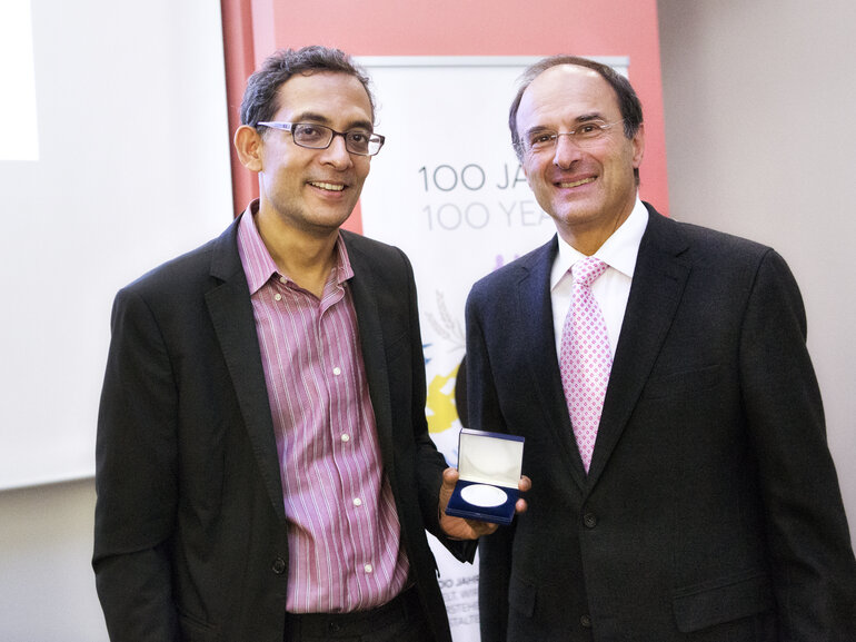 Abhijit Banerjee and Dennis Snower smiling and showing the medal Banerjee received at the Bernhard Harms Prize ceremony.