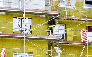 Thermal insulation of the facade of an apartment building with thick mineral rock wool plates using scaffolding