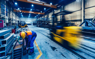 Factory work. Forklift moving and a worker taking a steel profile