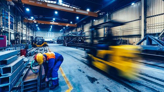 Factory work. Forklift moving and a worker taking a steel profile