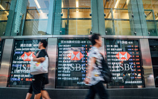 Pedestrians walking by a financial display board im Hongkong