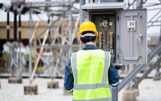 Engineer is working at high voltage substation performing inspection and check on power infrastructure to ensure safety and proper operation of electrical systems