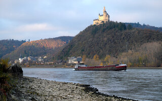 Der Rhein mit Niedrigwasser bei Braubach mit Binnenschiff und Marksburg