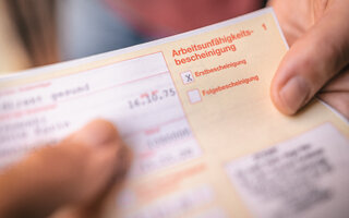 Arbeitsunfähigkeitsbescheinigung wird übergeben