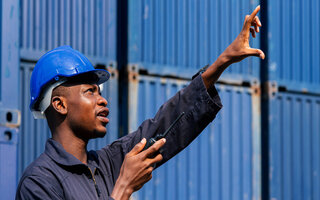 black african american man worker working control loading freight containers at commercial shipping dock