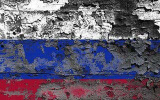 Painted colors of the Russian flag peeling off a wooden wall