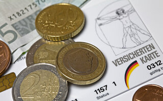 Euro coins on top of German Health insurance card