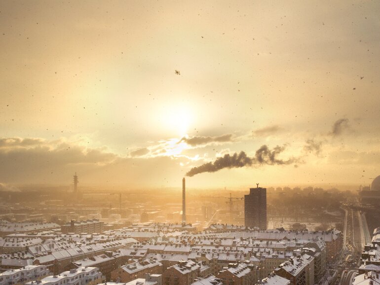 View over a city with snow-covered roofs and a smoking industrial chimney