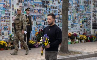 Ukraine President Selenskyj with flowers in his hands in front auf picture wall