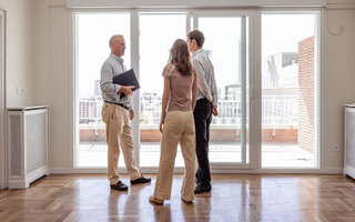 Real estate agent discussing a new property with a young couple in a modern apartment