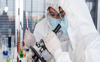 coronavirus covid-19 infected blood sample in sample tube on hand of scientist in biohazard protection clothing doing analysis to virus sample in laboratory