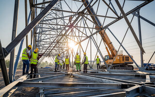 Construction crew assembling metal framework components of electrical transmission tower structure