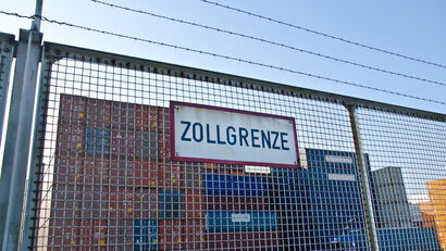 Schild am Zaun, Zollgrenze