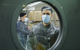 View into a kitchen with chefs wearing masks